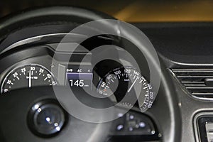 Speeding. A modern car with illumination of the dashboard close-up, moving at a speed of 146 km. Against the background