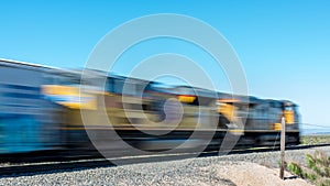 Speeding train engine passes at a railroad crossing in the deser