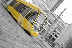 speeding yellow tram with black and white city background