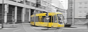 speeding yellow tram with black and white city background