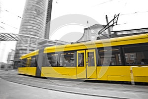 speeding yellow tram with black and white city background