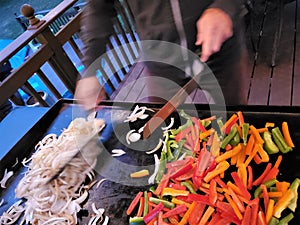 Rychlý šéfkuchař kuchaři cibule a zvon papriky na mřížka 