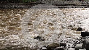 Speedy unclean river flowing into the rocks after heavy rain and flood