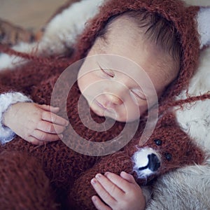 Speeping newborn baby detail in brown knitted wool overal with fox toy