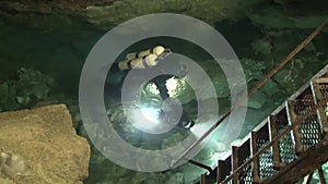 Speleodivers in diving suits descend into a cave lake, from which an underwater hole leads to the Orda underwater cave.