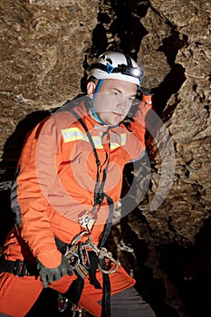 Speleologist descend by the rope in the deep vertical cave tunnel. Cave man hanging over abyss. View from the top og the tunnel.