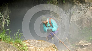 Speleologist descend by the rope in the deep vertical cave tunnel. Stock footage. Man hiker discovering unknown