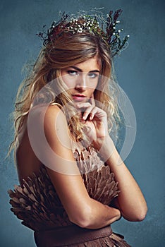 Spellbinding beauty. a young woman posing with flowers in her hair against a blue background.