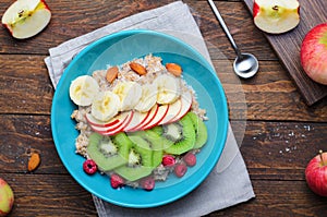 Spelt Porridge with Fruits in a Bowl over Wooden Background