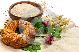 Spelt whole grain flour in ceramic bowl, wheat ears and homemade roll bun