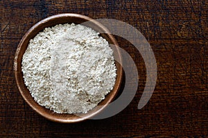 Spelt whole grain flour in dark wooden bowl isolated on dark bro