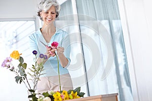 Spend a little time every day doing what you love. a senior woman enjoying some flower arranging at home.