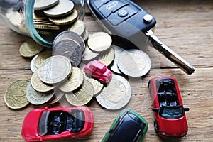 Spending all savings on a car concept with toy vehicle, money and car key on wooden background