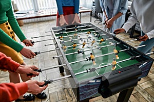 Spending great time together. Cropped photo of young people playing table soccer in the office. Having fun after work