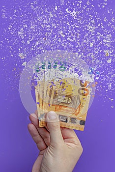 Spending money, spending all money is illiterate. The euro banknote turns to ash, dissolves against a purple background