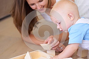 Spending quality time with mom. A young mother playing with building blocks along with her baby son.