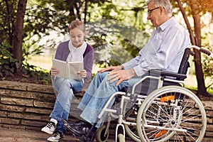 Spending time together reading book outdoor granddaughter and di