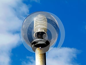 Sphere shaped street lamp lens under blue sky with white clouds