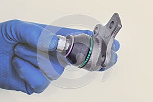 Spherical bearing. one of the elements in the car`s suspension. mounted on the lever. the master in blue gloves holds the detail.