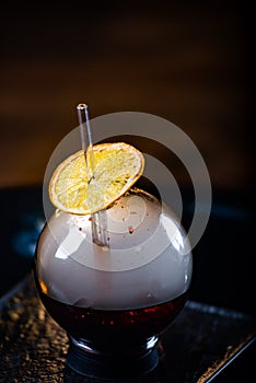 Spherical glass with smoke and alcohol. Caramelized Lemon Slices. Smoke on a black background