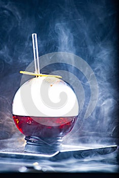 Spherical glass with smoke and alcohol. Caramelized Lemon Slices. Smoke on a black background