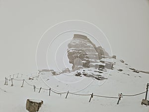 The Sphinx Sfinxul, a natural rock formation in the Bucegi Natural Park, in the Bucegi Mountains of Romania, during a blizzard