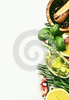 Spice mix, fresh spicy herbs: rosemary, green basil, red garlic, assorted pepper, olive oil on gray kitchen table, food cooking