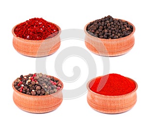 Spice selection of paprika, mixed spice, cayenne pepper, and allspice ground in wooden bowl, isolated on white