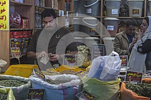 Spice seller on the Eastern Bazaar. A vendor counts money - Iranian rials