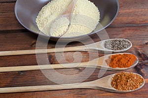 Spice on spoon with bowl of couscous