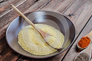 Spice on spoon with bowl of couscous