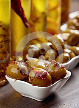 Spiced green olives and bottles with olive oil .