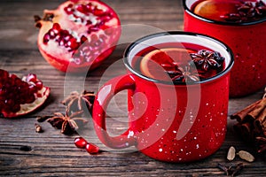 Spiced Pomegranate Apple Cider Mulled Wine Sangria in red mugs on wooden background.