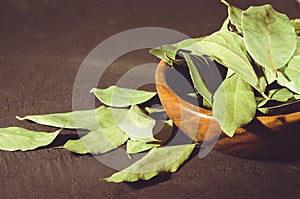 Spices of bay leaf in rural style/bay leaf in a wooden bowl on a black stone background. selective focus