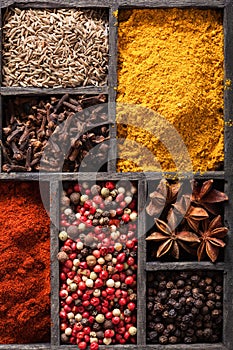 spices in box: pink and black pepper, ground paprika, curry, anise; clove; cumin