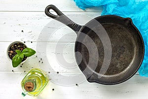 Spices and a cast-iron frying pan on a white wooden kitchen table. Culinary background