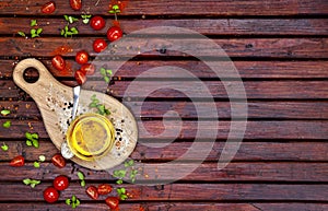 Spices, cherry tomatoes, basil and vegetable oil on dark wooden table, top view