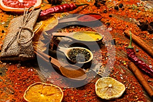 Spices concept. Spices scattered all over wooden surface. Spoons filled with cinnamon, grinded red pepper and curcuma