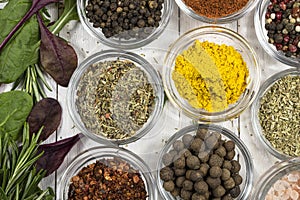 Spices and fresh herbs on a white wooden background close-up