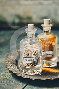 Spices-ginseng and turmeric- in bottles on rustic background, close up photo