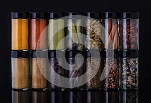 Spices in glass jars on a black background.