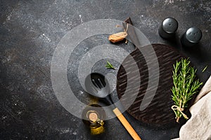 Spices and herbs with craft cutting board at black background.