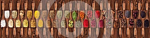 Spices and herbs from different countries in wooden spoons. Colorful seasonings on table background, top view