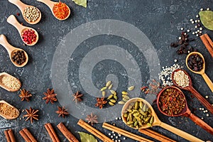 Spices and herbs over black stone background.