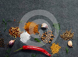 Spices and herbs over black stone background.