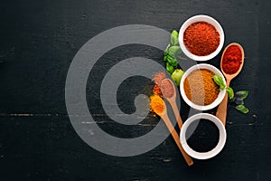 Spices and herbs on a wooden board. Pepper, salt, paprika, basil, turmeric. On a black wooden chalkboard.