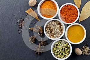 Spices in little white bowls on black slate background - Indian spice - top view photo