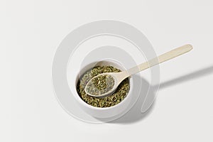 Spices mix of herbs in a ceramic bowl with a wooden spoon on a white isolated background. Concept of aromatic cooking, Ayurvedic