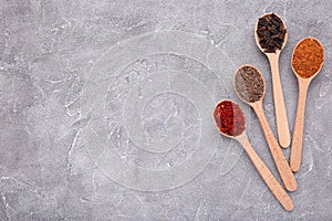 Spices mix on wooden spoons on a grey background. Top view