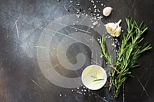 Spices, olive oil and herbs on a dark stone or slate table. Ingredients for cooking. Food background.